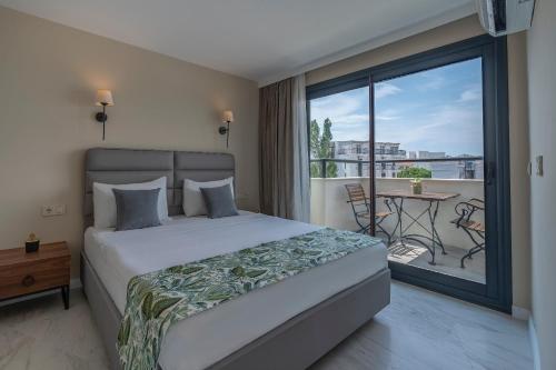 a bedroom with a bed and a balcony with a table at Rosy Suites Hotel in Kuşadası