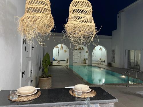 una piscina con 2 platos y 2 lámparas de araña en Villa Sans Vis à Vis Le Domaine Luxury Experience, en Mezraya