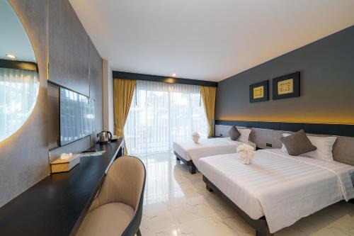 a hotel room with two beds and a window at LHC HOTEL AND RESORT in Pattaya Central