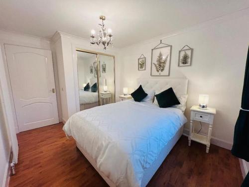 um quarto com uma grande cama branca e um lustre em A Stylish Two-Bedroom Flat-Free Parking-CityCentre em Aberdeen