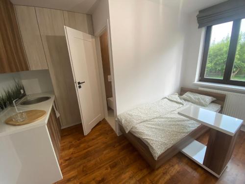 a small bedroom with a bed and a desk and a window at Miejska Stodoła in Biała Podlaska