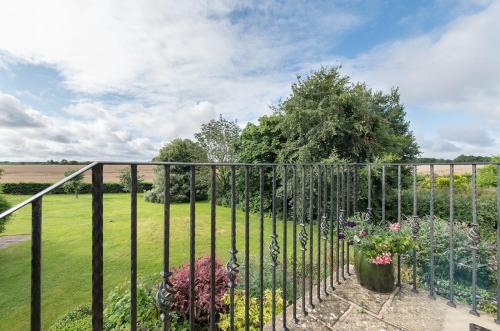 a wrought iron fence with flowers in a yard at Exquisite Coach House Near Silverstone & Stowe in Buckingham