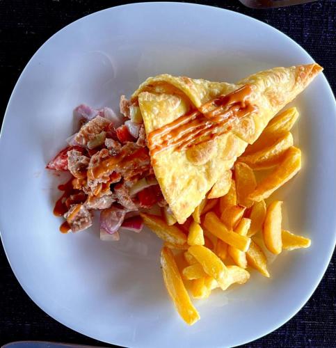 a plate of food with a pie and french fries at Mwamba Kelele Lodge in Fort Portal