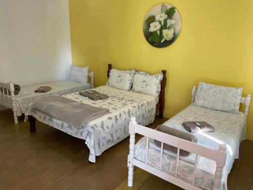 a room with two beds and a clock on the wall at Pousada Cirandinha in Itajaí