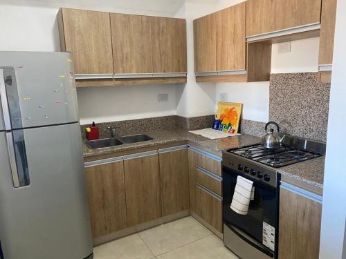 cocina con armarios de madera y refrigerador blanca en Alquilerpordiapuertomadryn en Puerto Madryn
