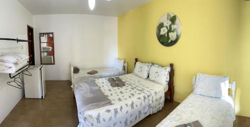 a bedroom with two beds and a clock on the wall at Pousada Cirandinha in Itajaí
