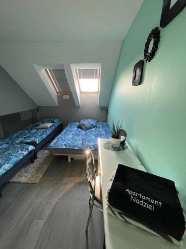 a room with two beds and a table in it at Apartament Nadziei in Chmielno