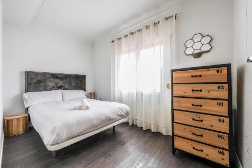 um quarto com uma cama, uma cómoda e uma janela em apartamento en plaza de ventas em Madrid