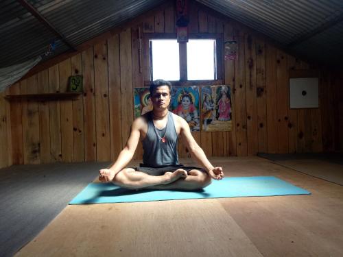 a man sitting on a yoga mat in a room at Mount Mahabharat Homestay in Panaoti