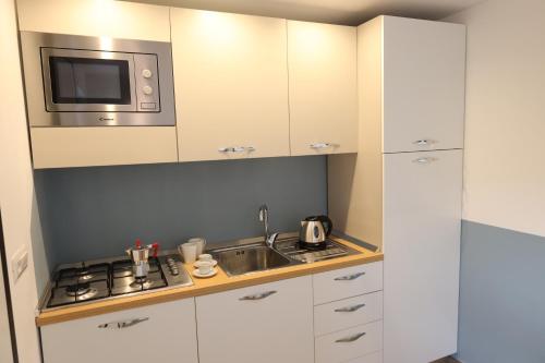 a kitchen with white cabinets and a sink and a microwave at SUNSEA - Enjoy Your Family in Capo Vaticano