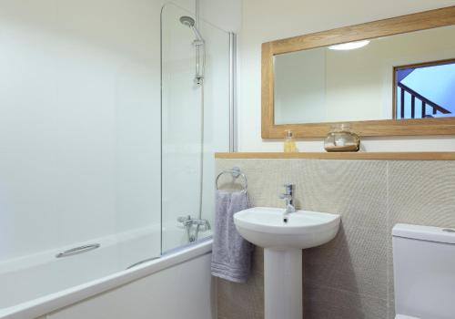 W łazience znajduje się umywalka, toaleta i lustro. w obiekcie Osprey Lodge w mieście Kingussie