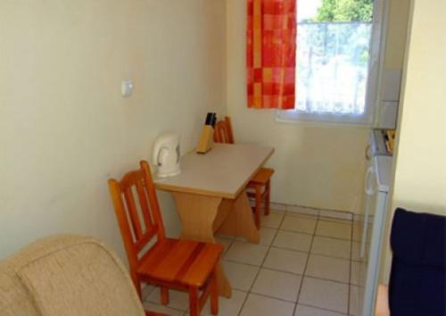 a kitchen with a table and two chairs and a table and a window at Domki letniskowe Aneta in Trzęsacz