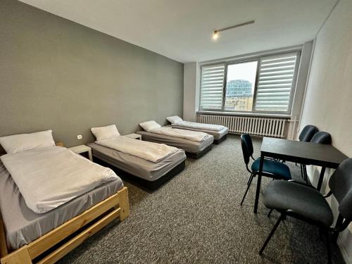 a room with three beds and a desk and a table at BLUE Hostel - Private Rooms by Friendly Hostel in Poznań