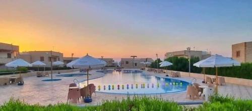 une grande piscine avec des chaises et des parasols dans un complexe dans l'établissement شاليه في قرية هيلو بيتش في الكيلو ٥٠, à Borg El Arab