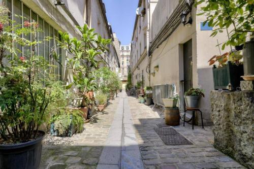 un callejón vacío con macetas y edificios en Heart of Paris Apartment en París
