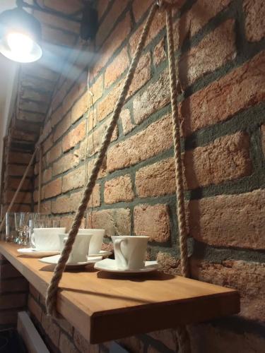 a table with cups and saucers on a brick wall at Apartamenty i pokoje gościnne "Wacuś" in Srebrna Góra