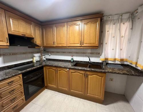 een keuken met houten kasten en een spoelbak bij Puerto Romano Denia in Denia