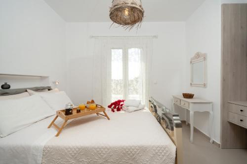a white bedroom with a bed with a table on it at Santa Maria Mare in Naousa