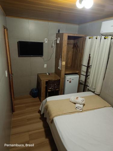 a small bedroom with a bed and a television at Florcamará POUSADA in Camaragibe