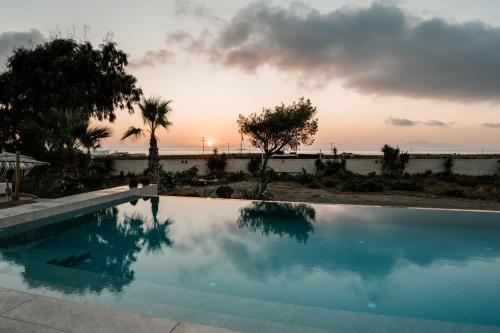 einen Pool mit Sonnenuntergang im Hintergrund in der Unterkunft Echo Villa in Fira