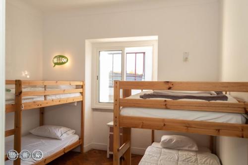 2 łóżka piętrowe w pokoju z oknem w obiekcie The Shed Surf Lodge w Costa de Caparica