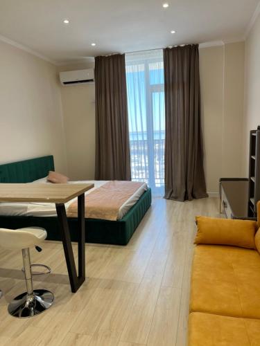 Aktau Reviera 1 ком апартамент في Ömirzaq: غرفة نوم بسرير وطاولة واريكة