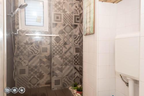La salle de bains est pourvue d'une douche avec une porte en verre. dans l'établissement The Shed Surf Lodge, à Costa da Caparica