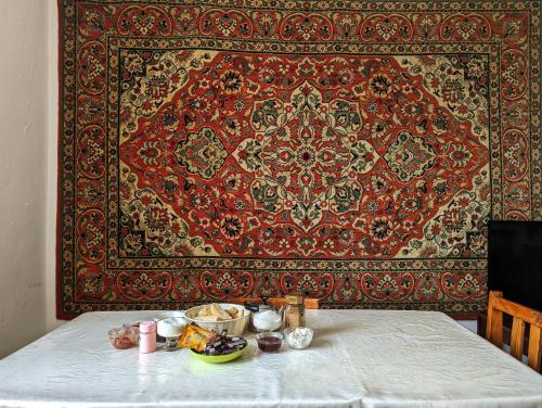 une table avec un tapis et une table avec de la nourriture dans l'établissement Baisal Guest House, à Orto-Saz