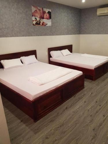 2 Einzelbetten in einem Zimmer mit Holzböden in der Unterkunft Guest House Phú Tân in Hà Tiên