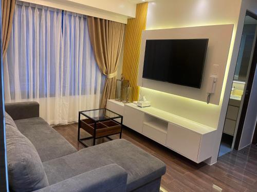 a living room with a couch and a flat screen tv at E & T Homecation 2 Bedroom at SMDC Air Residences in Manila