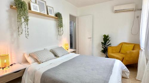 1 dormitorio con 1 cama y 1 silla amarilla en Cozy 2 bedroom apartment in Nahariya, en Nahariyya