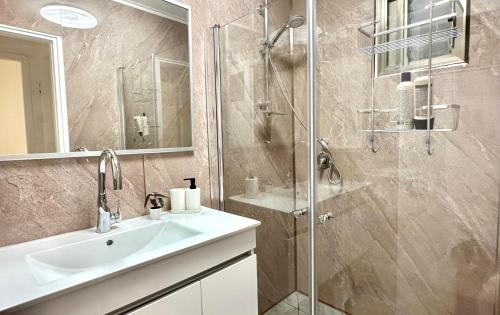 y baño con lavabo y ducha acristalada. en Cozy 2 bedroom apartment in Nahariya, en Nahariyya