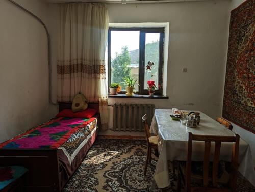 Cette chambre comprend une table, un lit et une fenêtre. dans l'établissement Baisal Guest House, à Orto-Saz