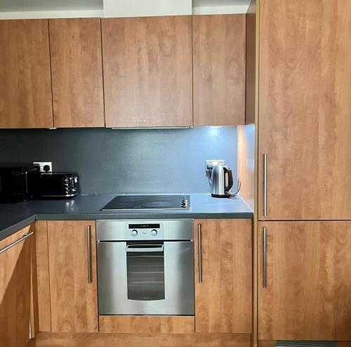 a kitchen with a stove and wooden cabinets at The Cube Side Apartments - One Bedroom With Balcony in Birmingham
