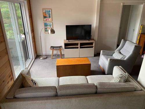 sala de estar con sofá, 2 sillas y TV en Willow Cabin- North Frontenac Lodge en Ompah