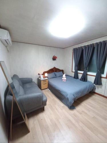 een slaapkamer met een bed, een bank en een stoel bij A full private home in Seoul
