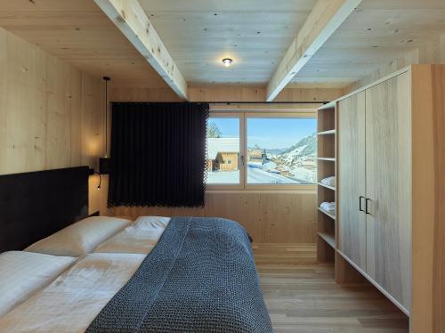 een slaapkamer met een groot bed en een groot raam bij Tinn Naturchalet in Mittelberg