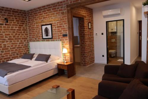 um quarto com paredes de tijolo, uma cama e um sofá em APARTAMENT PRZY RYNKU em Chełmno