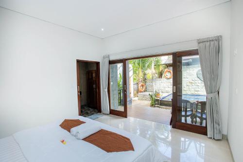 a white bedroom with a bed and a sliding glass door at Pondok Raamshanti Lembongan in Nusa Lembongan