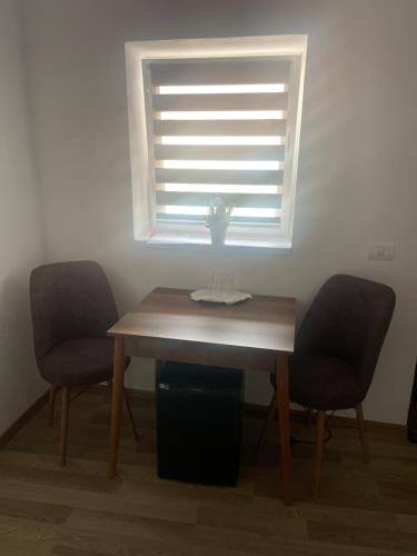 a dining room table with two chairs and a window at Casa Marko in Nădlac