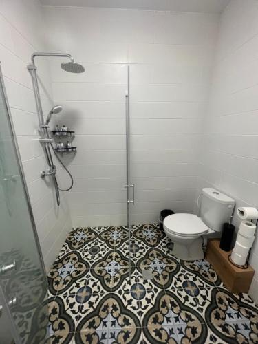 a bathroom with a shower and a toilet with a tile floor at Lana's Guest House in Ḥurfeish