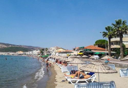 een strand met veel mensen die op stoelen en parasols zitten bij Stylish 3 room apartment with amazing sea views in Dikili