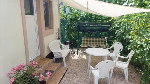 um pátio com cadeiras brancas, uma mesa e uma cerca em Oázis Apartman, Gárdony, Velencei-tó em Gárdony