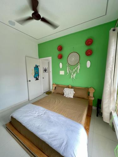 a bedroom with a bed with a green wall at Boho - By Great Impressions in Pune