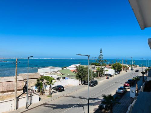 a street with cars parked on the road and the ocean at Appartement en bord de mer in Pont Blondin