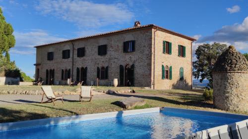 een oud gebouw met een zwembad ervoor bij Podere Campiano in Volterra