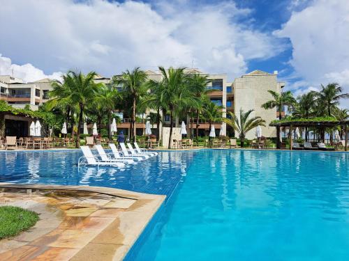 una gran piscina con sillas blancas y palmeras en Apto 3 quartos no Wai Wai - Cumbuco-Ce en Cumbuco