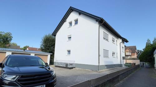 a car parked in front of a white house at Moderne Dachgeschosswohnung Modern Apartment in Rastatt