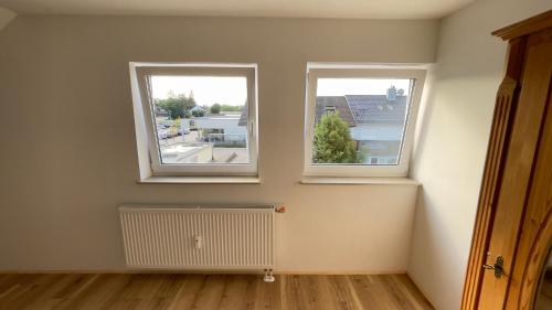 an empty room with two windows and a radiator at Casa Grande mit 3 Apartments in Rastatt