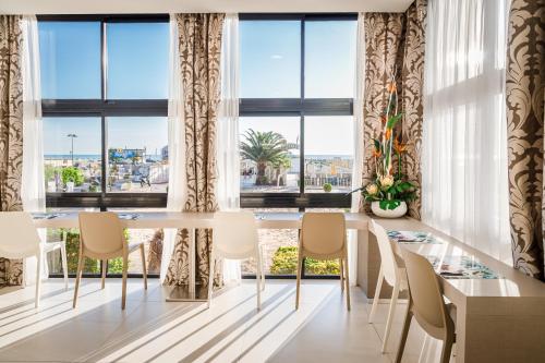 ein Esszimmer mit einem Tisch und Stühlen sowie großen Fenstern in der Unterkunft Hotel Ariane - BEACHFRONT, Breakfast XXL & Brunch in Rimini